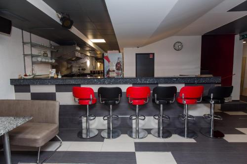 a bar with red and black chairs in a room at Penzion Hviezda in Bratislava