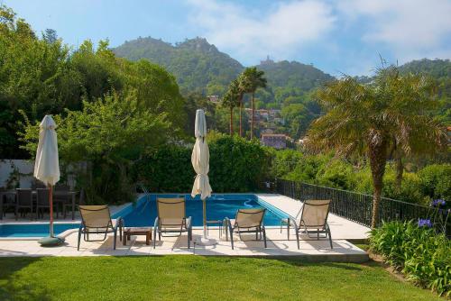 a group of chairs and umbrellas next to a swimming pool at Casa do Valle in Sintra