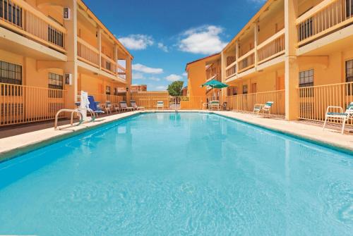 a large pool in a hotel with chairs and umbrellas at Baymont by Wyndham Lubbock - Downtown Civic Center in Lubbock