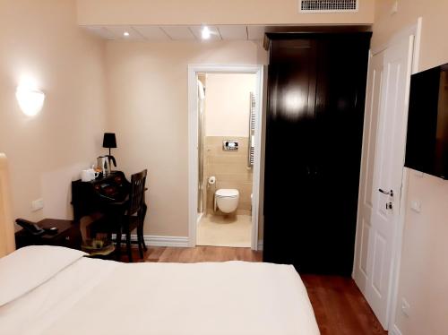 a bedroom with a bed and a bathroom with a toilet at Hotel Patavium in Padova