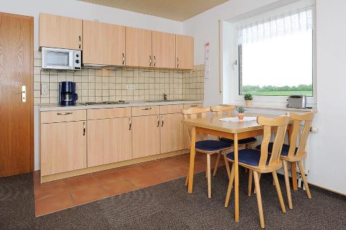 eine Küche mit einem Tisch, Stühlen und einer Mikrowelle in der Unterkunft Ferienwohnung Trautes Heim in Bensersiel