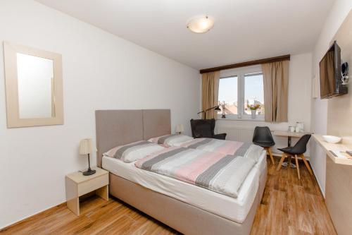 a white bedroom with a bed and a desk at Penzion Hviezda in Bratislava