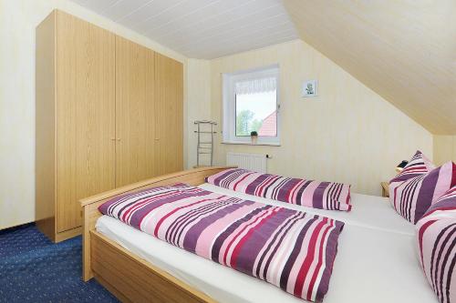 1 Schlafzimmer mit 2 Betten und gestreifter Bettwäsche in der Unterkunft Ferienwohnung Trautes Heim in Bensersiel