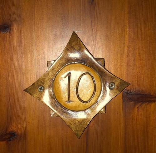 a metal plaque with the number on a wooden wall at Ξενώνας Πατρικό in Neraïdochóri