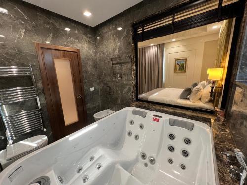 uma casa de banho com uma banheira e um espelho grande em Hotel Golden Palace em Shkodër