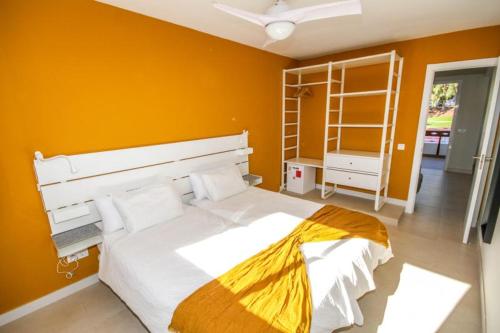 1 dormitorio con 1 cama grande y pared de color naranja en New Miami Playa Apartamentos, en San Agustín