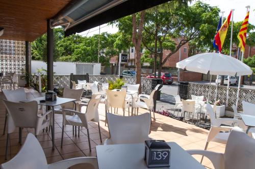 a restaurant with white chairs and tables and umbrellas at Hotel 139 in Castelldefels