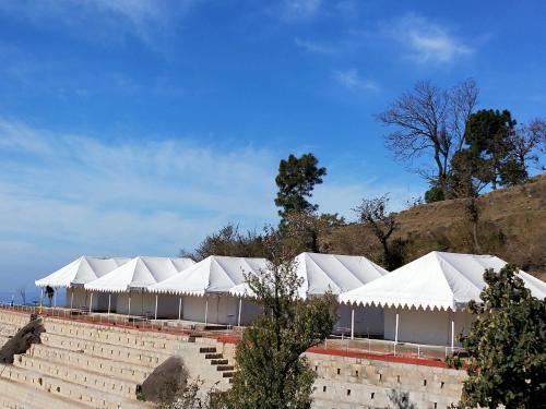 a row of white tents in front of a hill at Hill Ventures Adventure Camp and Restaurant in Dharamshala