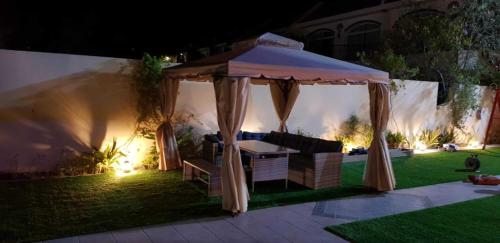 a gazebo with a table and chairs in a yard at night at درة العروس فيلا الازرق بيتش in Durat  Alarous