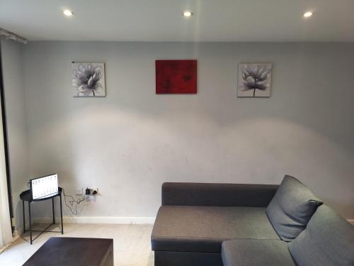 a living room with a couch and three pictures on the wall at Cornhill Apartment by Serviced Living Liverpool in Liverpool