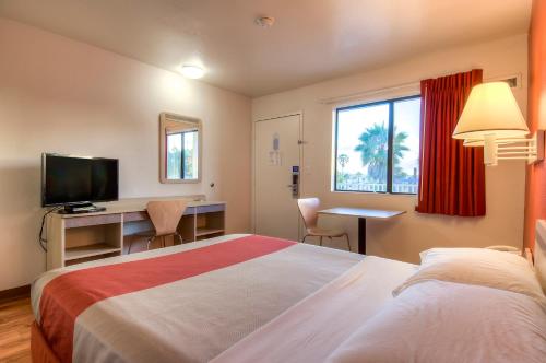 a hotel room with a bed and a desk and a television at Motel 6-Oceanside, CA in Oceanside