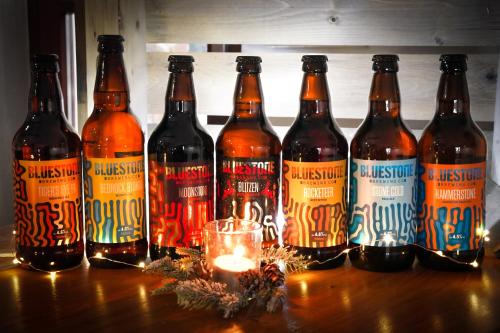 a group of beer bottles on a table with a candle at Jabajak Vineyard Restaurant & Rooms in Whitland