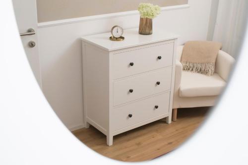 a white dresser with a chair and a mirror at Cozy apartments in Ljubljana