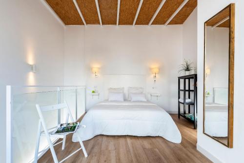 1 dormitorio blanco con 1 cama y 1 silla en HSH Suites Santa Catalina, en Sevilla