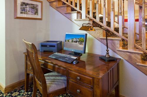 a desk with a computer on it with a staircase at AmericInn by Wyndham White Bear Lake St. Paul in White Bear Lake