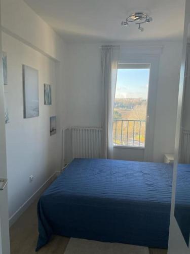 une chambre avec un lit bleu et une fenêtre dans l'établissement appartement neuf style architecte au calme, à Compiègne