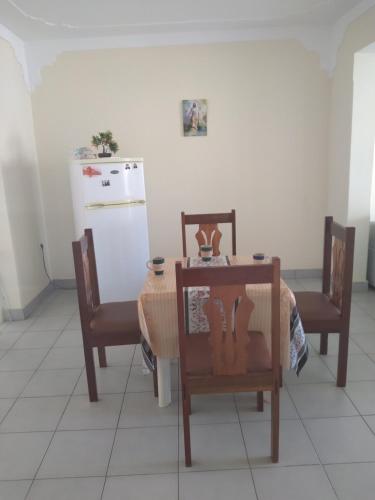 cocina con mesa, sillas y nevera en Pensão Domingas, en São Filipe