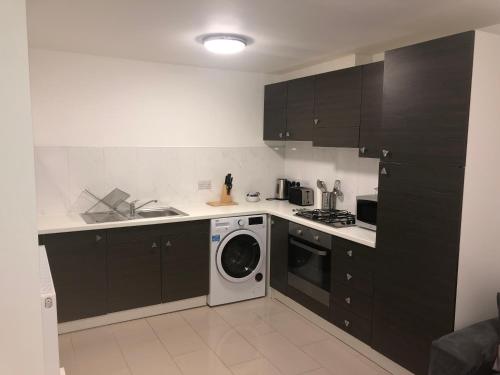 a kitchen with black cabinets and a washing machine at 2 bedroom Large Town Centre Apartment FREE Parking in Loughborough