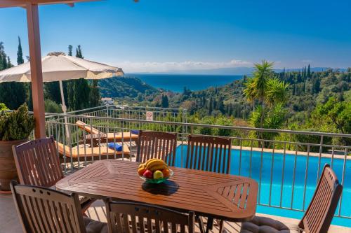 a table with a bowl of fruit on it on a balcony at Villa Mounda Apollon in Ratzaklíon