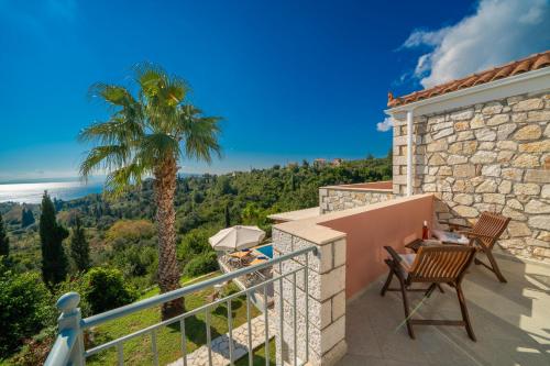 a balcony with a table and chairs and a palm tree at Villa Mounda Apollon in Ratzaklíon