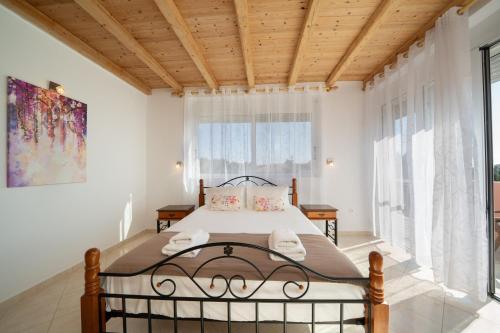 a bedroom with a bed and a large window at Villa Mounda Apollon in Ratzaklíon