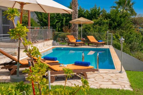 a pool with chairs and umbrellas next to a house at Villa Mounda Apollon in Ratzaklíon