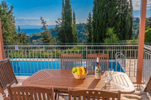 a wooden table with a basket of fruit and a bottle of wine at Villa Mounda Hermes in Ratzaklíon