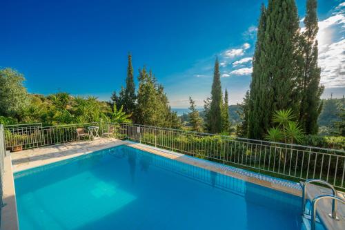 a swimming pool with a fence and trees at Villa Mounda Hermes in Ratzaklíon