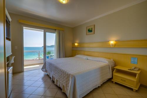 a bedroom with a bed with a view of the ocean at Bombinhas Blue Suítes in Bombinhas