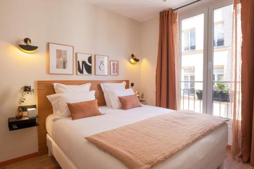 Schlafzimmer mit einem großen weißen Bett und einem Fenster in der Unterkunft Tinah Paris, Aboukir in Paris
