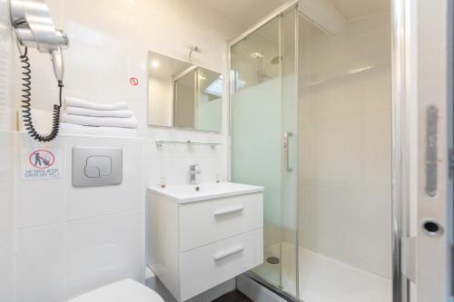 a white bathroom with a shower and a sink at Hôtel Edmond Rostand in Marseille
