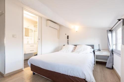 a white bedroom with a large bed with white sheets at Hôtel Edmond Rostand in Marseille