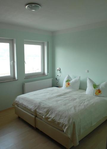 a bedroom with a white bed with two windows at Gastehaus Weingut Rossler in Lorch am Rhein
