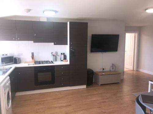 een keuken met zwarte kasten en een fornuis met oven bij Large Ground Floor Pet Friendly 2 Bedroom Apartment with FREE Parking in Loughborough