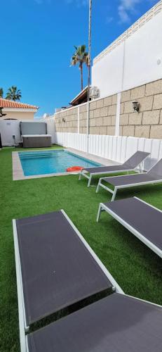 a backyard with a swimming pool and green grass at Villa Rosa in Callao Salvaje