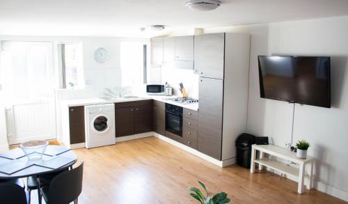 a kitchen with a washer and dryer and a table at Spacious Ground Floor 2 Bed Apartment Free Parking Pet Friendly in Loughborough