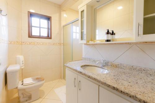 a bathroom with a sink and a toilet and a mirror at Pousada Areias do Rosa in Praia do Rosa