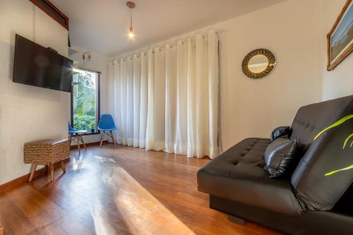 a living room with a couch and a flat screen tv at Pousada Areias do Rosa in Praia do Rosa