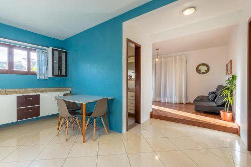 a kitchen and dining room with blue walls and a table and chairs at Pousada Areias do Rosa in Praia do Rosa