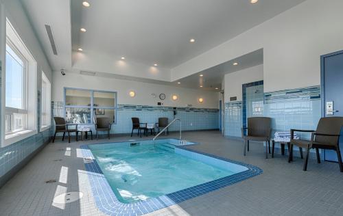 a large swimming pool in a room with chairs and tables at Canalta Lac La Biche in Lac La Biche