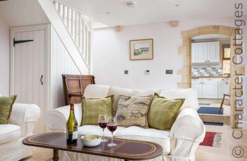 a living room with a white couch and a table with wine glasses at Oyster Barn in Naunton