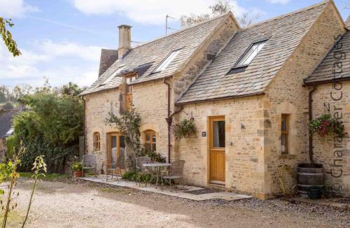 a brick house with a table and chairs in front of it at Oyster Barn in Naunton
