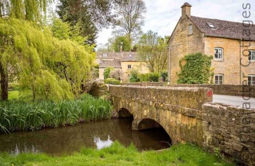 an old stone bridge over a river in a village at Oyster Barn in Naunton