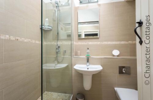 a bathroom with a shower and a sink and a mirror at Lanes Cottage in Chipping Campden