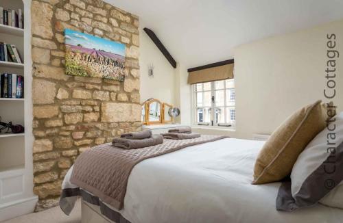 ein Schlafzimmer mit einem großen Bett mit einer Steinwand in der Unterkunft Lanes Cottage in Chipping Campden