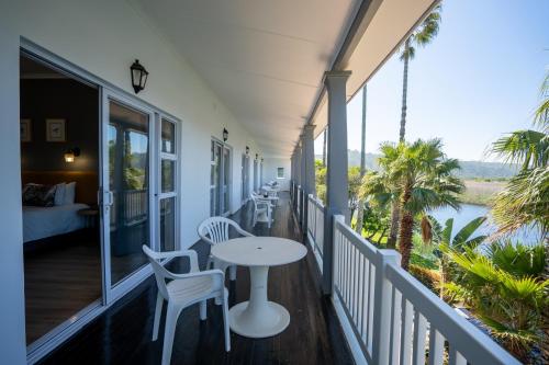 a porch with a table and chairs and a bed at Fairy Knowe Hotel in Wilderness