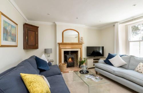 a living room with a blue couch and a fireplace at Copperbeech in Stow on the Wold
