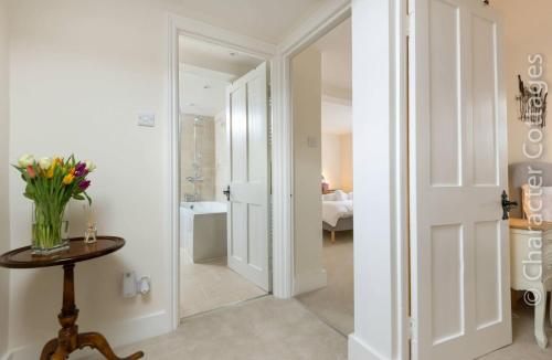 een kamer met een hal met een vaas met bloemen op een tafel bij Wall Cottage in Burford