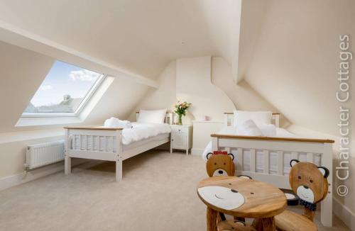 een slaapkamer op zolder met 2 bedden en een tafel bij Wall Cottage in Burford