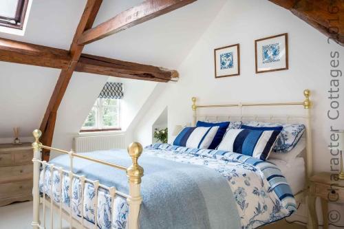 a bedroom with a bed with blue and white pillows at Primrose Cottage Blockley in Blockley